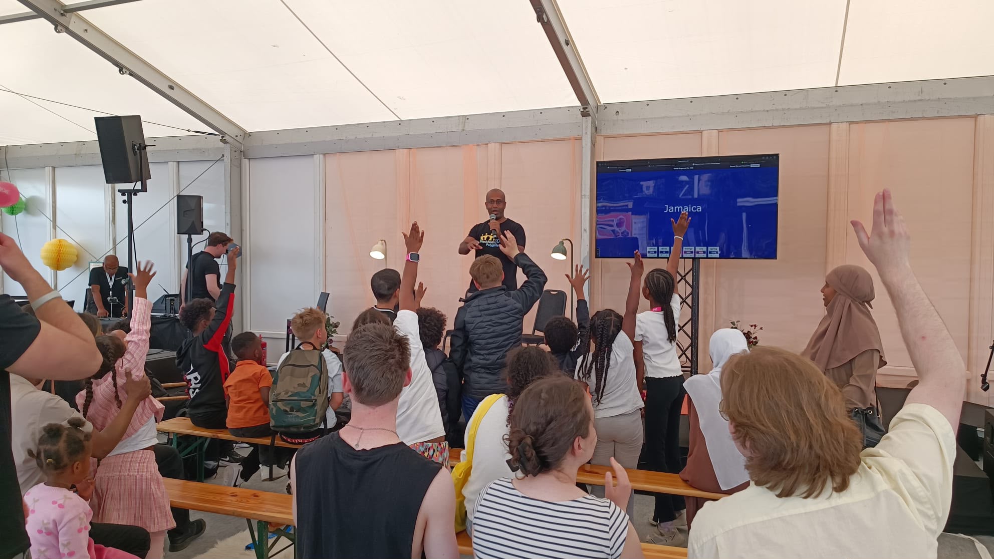 Kids raising their hands during a country-flag quiz at a community festival